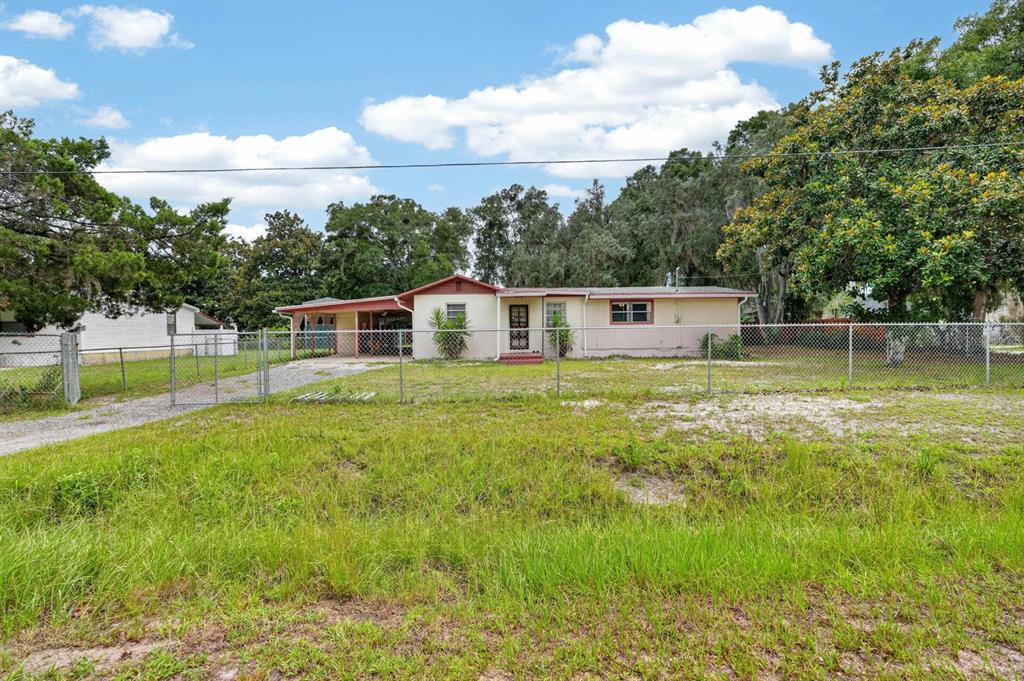 A single-story house with a carport and chain-link fence sits on a grassy lot — 131 DUNN AVENUE, SAN MATEO, FL
