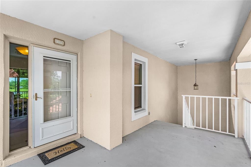 A covered entryway features a white front door, a side window, and a white railing — 14008 WILLOW GLEN COURT UNIT 210, PORT CHARLOTTE, FL