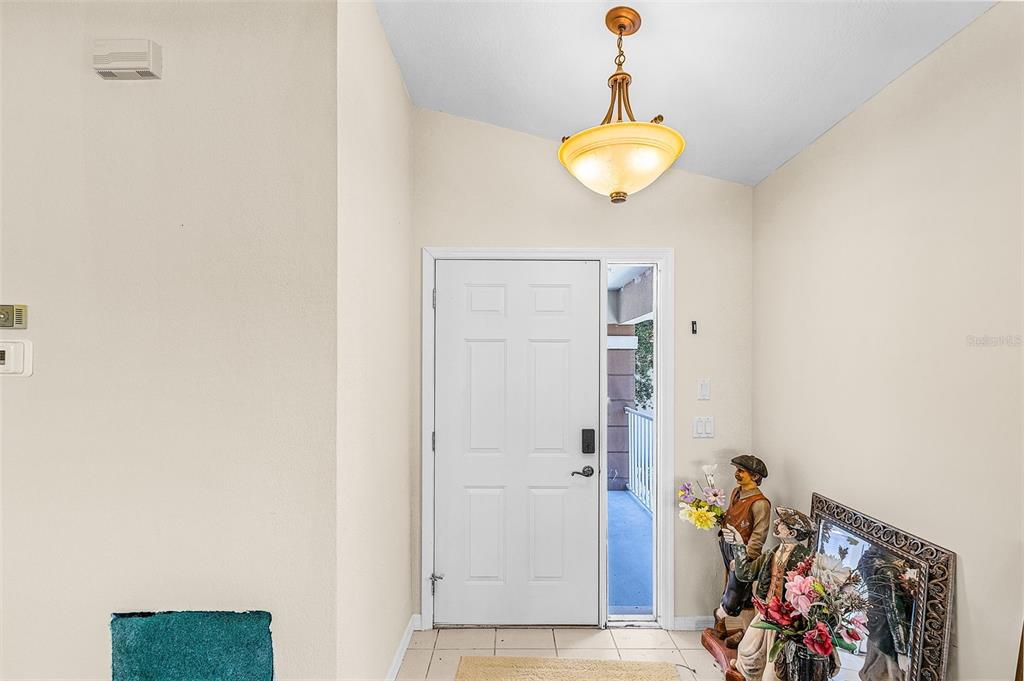 An entryway features a white front door, a pendant light, and decorative figurines — 14008 WILLOW GLEN COURT UNIT 210, PORT CHARLOTTE, FL