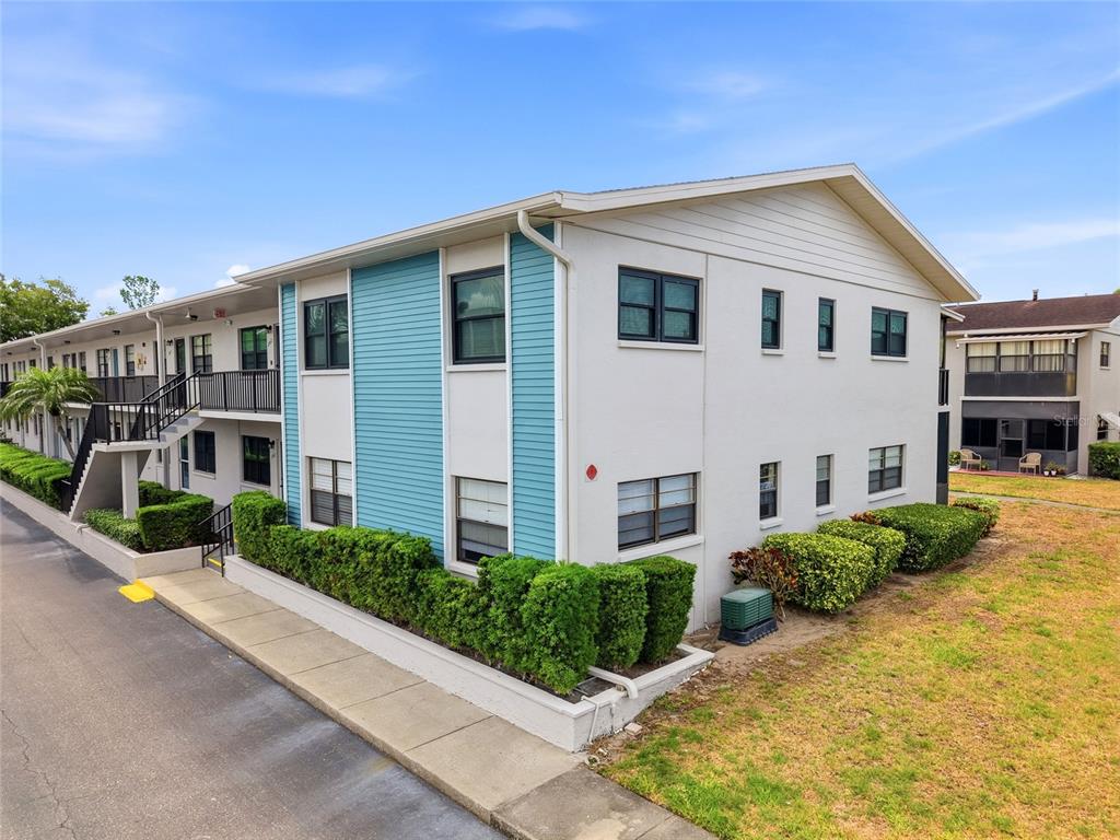 An exterior view of a two-story apartment building with blue siding and a concrete walkway — 5967 TERRACE PARK DRIVE N UNIT 201, ST PETERSBURG, FL