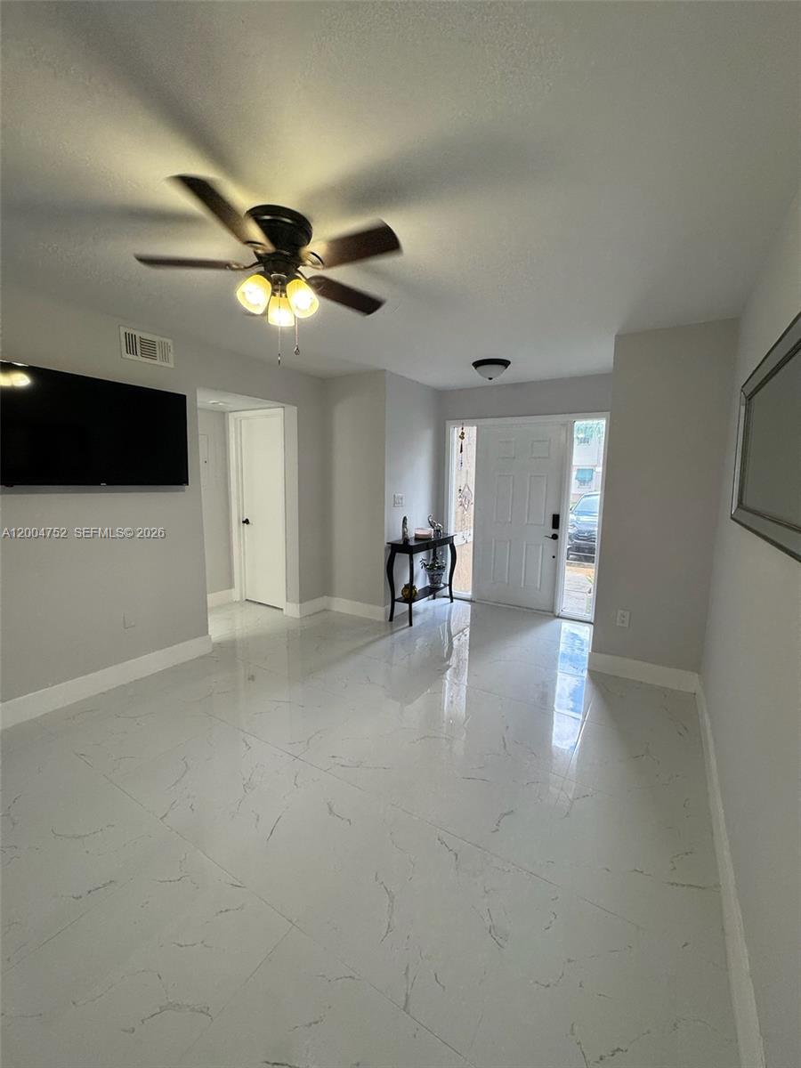 A bright living room features white marble-look tile floors, a ceiling fan, and an entryway — 5127 SW 123rd Ave, Cooper City FL 33330, COOPER CITY, FL