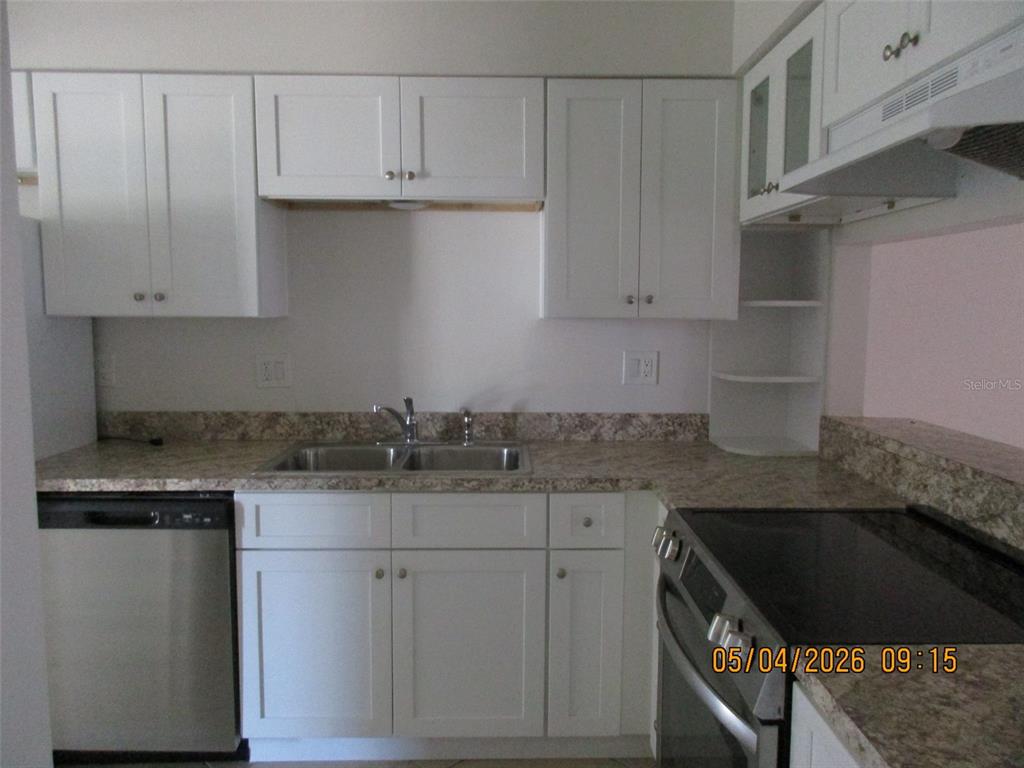 A kitchen features white cabinets, stainless steel appliances, and a speckled laminate countertop — 2112 BAHAMAS COURT, KISSIMMEE, FL