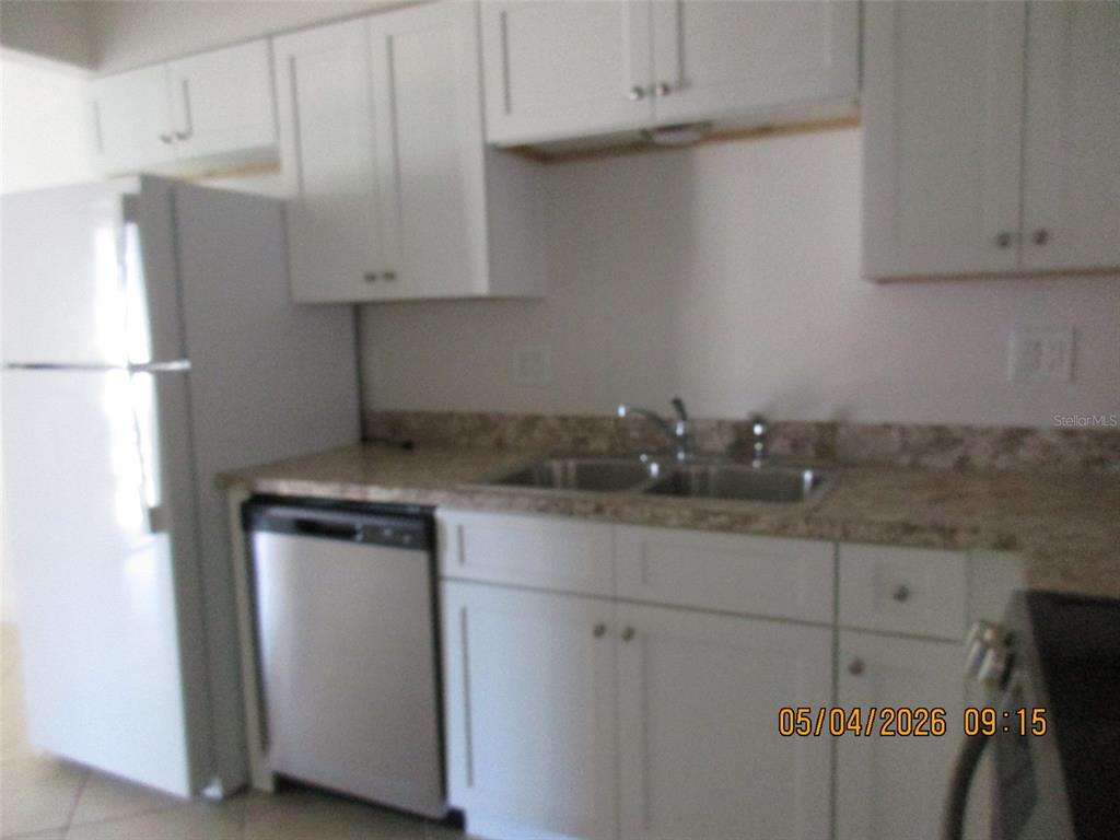 A kitchen features white cabinets, a stainless steel dishwasher, and a double-basin sink — 2112 BAHAMAS COURT, KISSIMMEE, FL