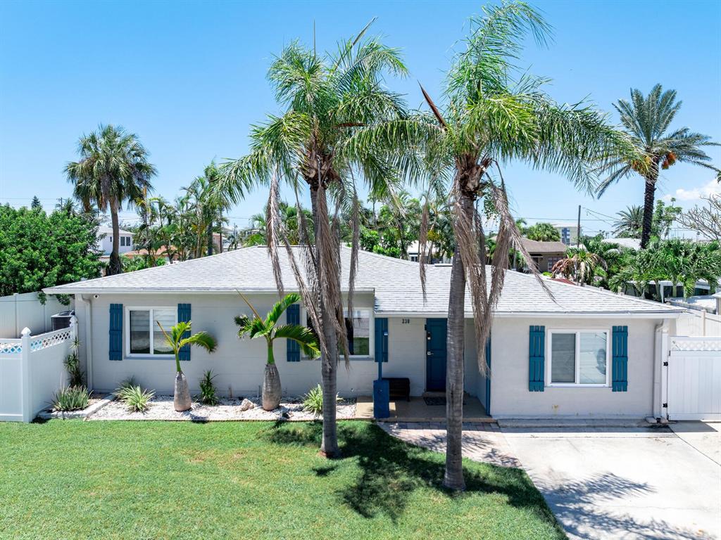 A single-story house with a light-colored exterior, blue shutters, and palm trees in the yard — 230 144TH AVENUE, MADEIRA BEACH, FL