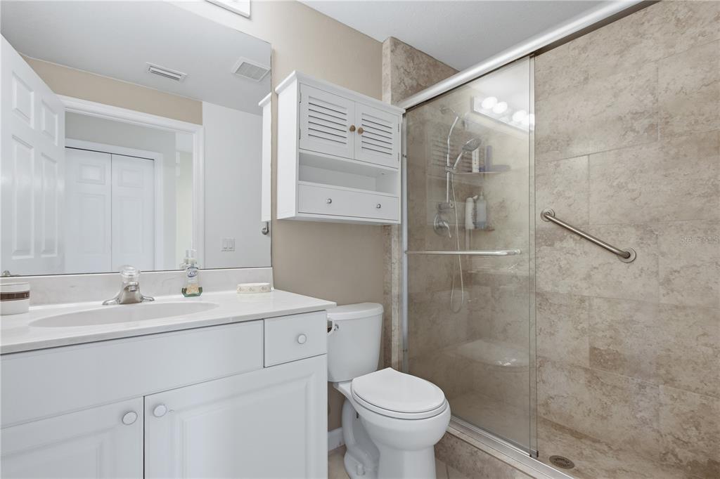 A bathroom features a white vanity, a toilet, and a glass-enclosed shower with tiled walls — 3010 MEANDERING WAY UNIT 101, FORT MYERS, FL