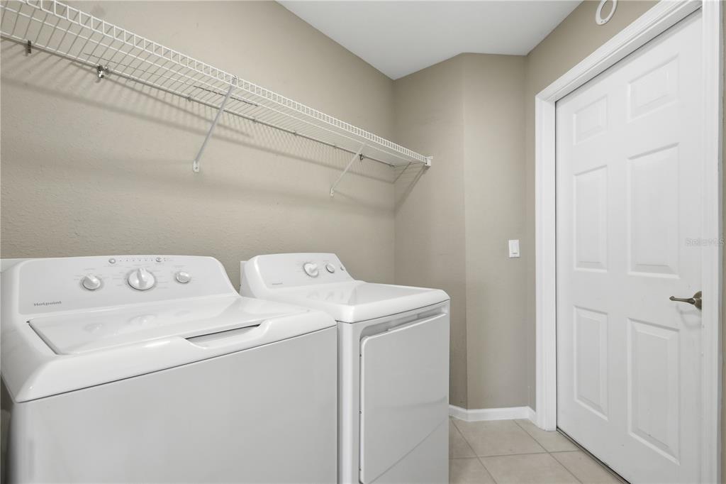 A laundry room features white appliances, a wire wall shelf, and a closed white door — 3010 MEANDERING WAY UNIT 101, FORT MYERS, FL