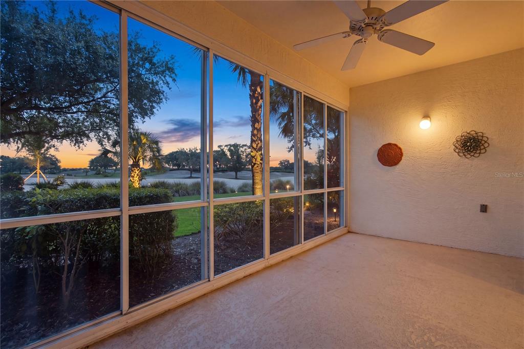 A screened-in porch with a ceiling fan overlooks a golf course at sunset — 3010 MEANDERING WAY UNIT 101, FORT MYERS, FL