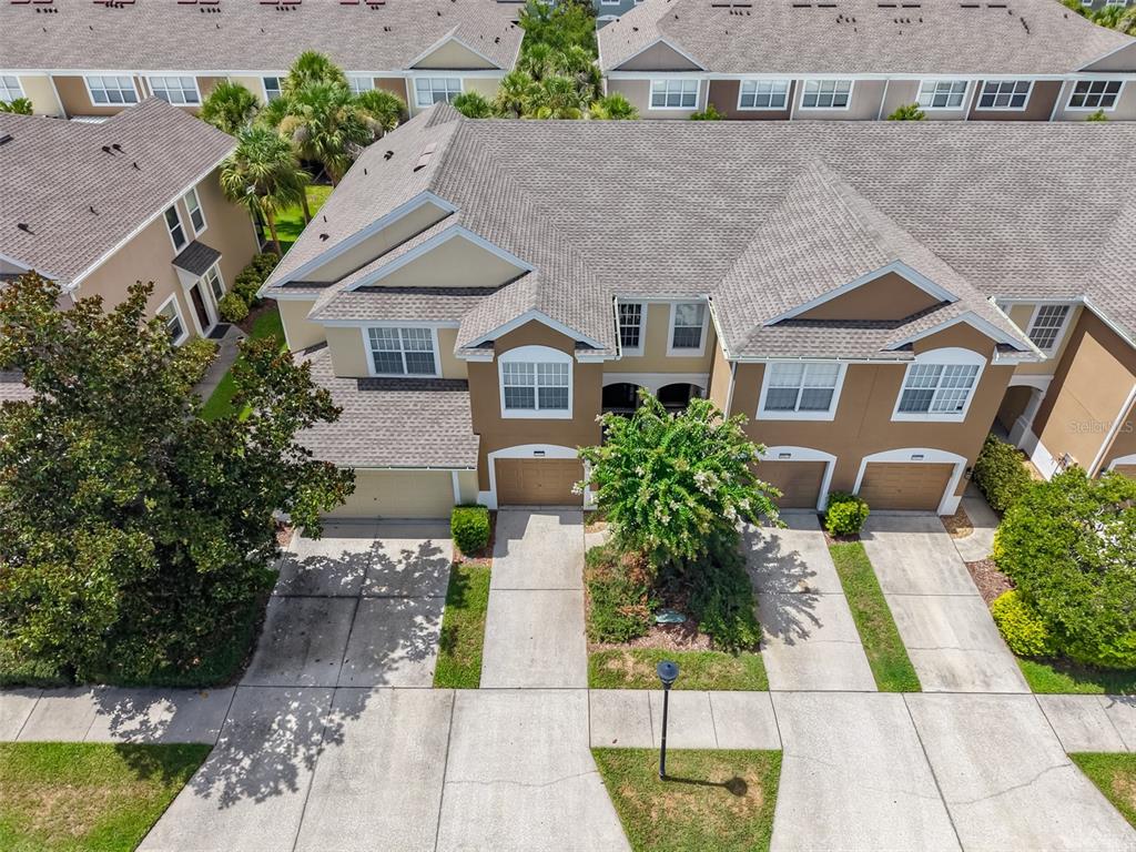 An aerial view shows a row of multi-story townhouses with attached garages and concrete driveways — 10141 POST HARVEST DRIVE, RIVERVIEW, FL