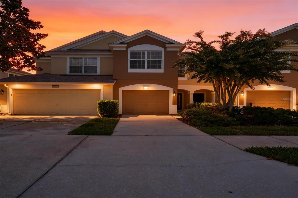 A two-story suburban house with three garage doors at sunset — 10141 POST HARVEST DRIVE, RIVERVIEW, FL