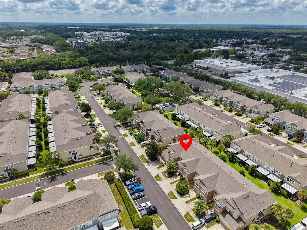 An aerial view shows a residential complex with multi-story townhomes, parking areas, and surrounding greenery — 10141 POST HARVEST DRIVE, RIVERVIEW, FL