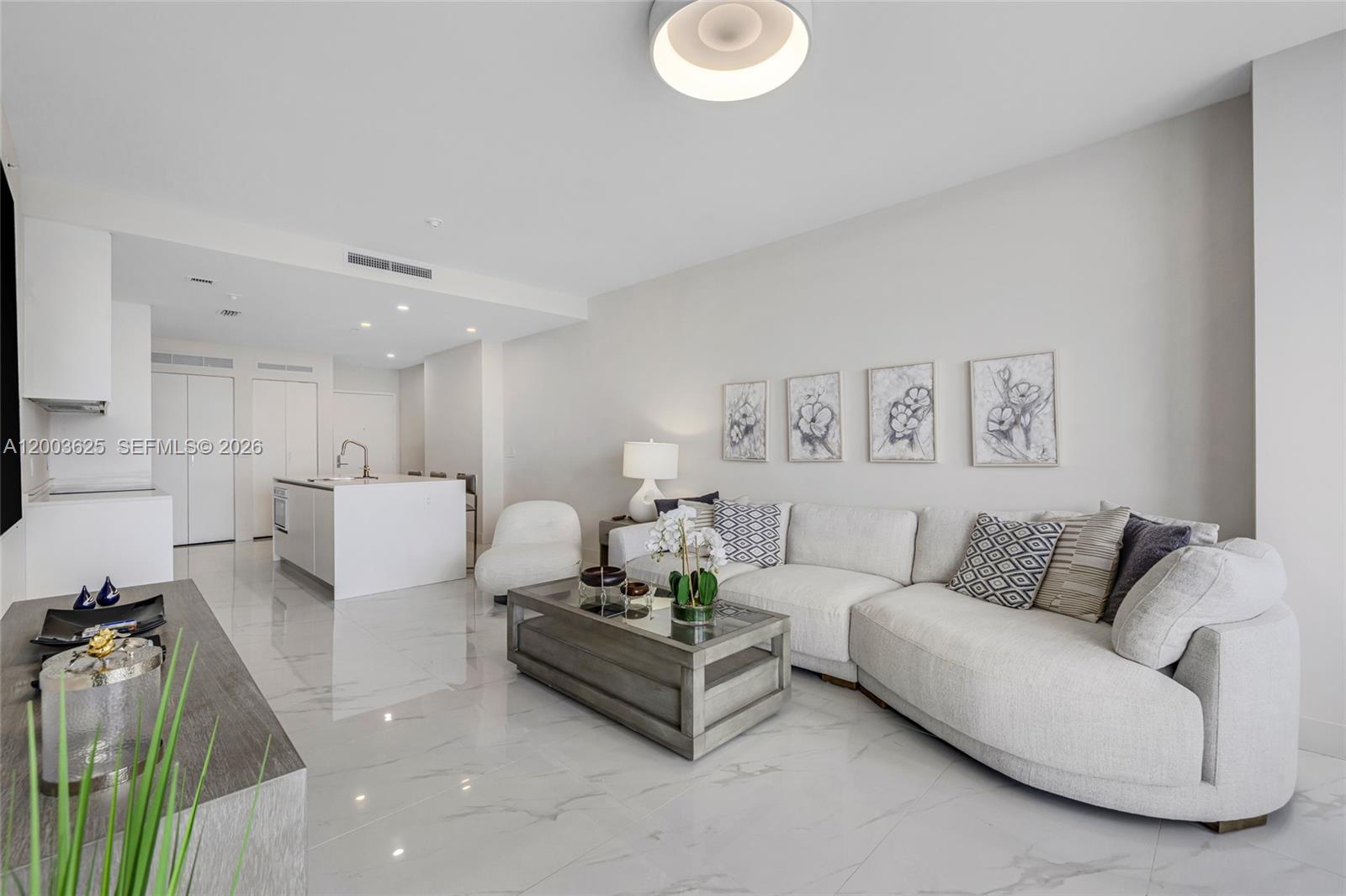 A modern living room features a white sectional sofa, a wooden coffee table, and marble flooring — 711 NE 23 # 704, Miami FL 33137, MIAMI, FL
