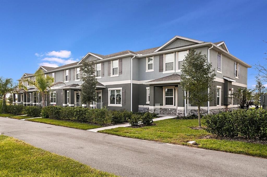 A multi-unit townhouse building features gray siding, stone accents, and a paved walkway — 2607 HARRIER COURT UNIT Sunset, APOPKA, FL