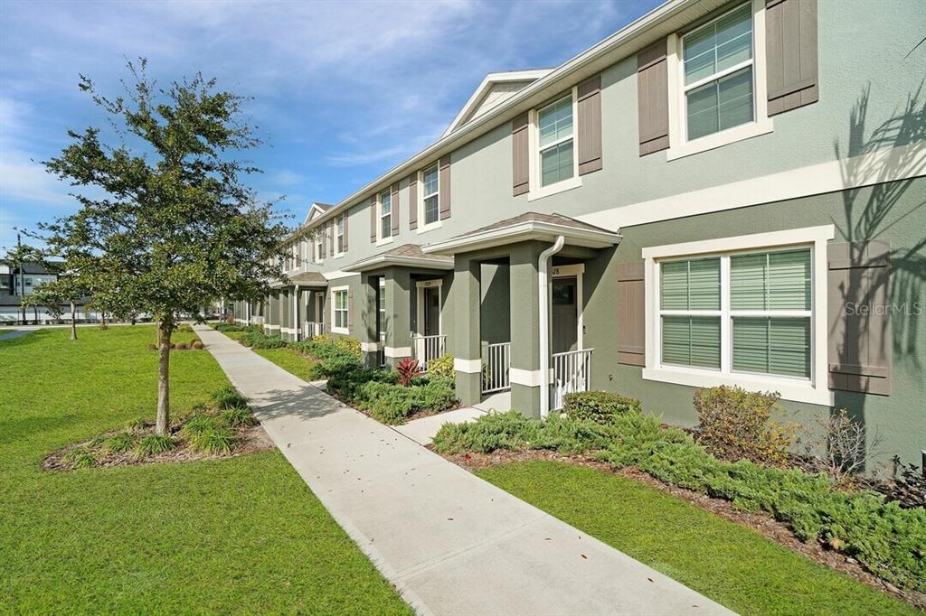 A row of two-story green townhomes with white trim and a concrete sidewalk in front — 2607 HARRIER COURT UNIT Sunset, APOPKA, FL