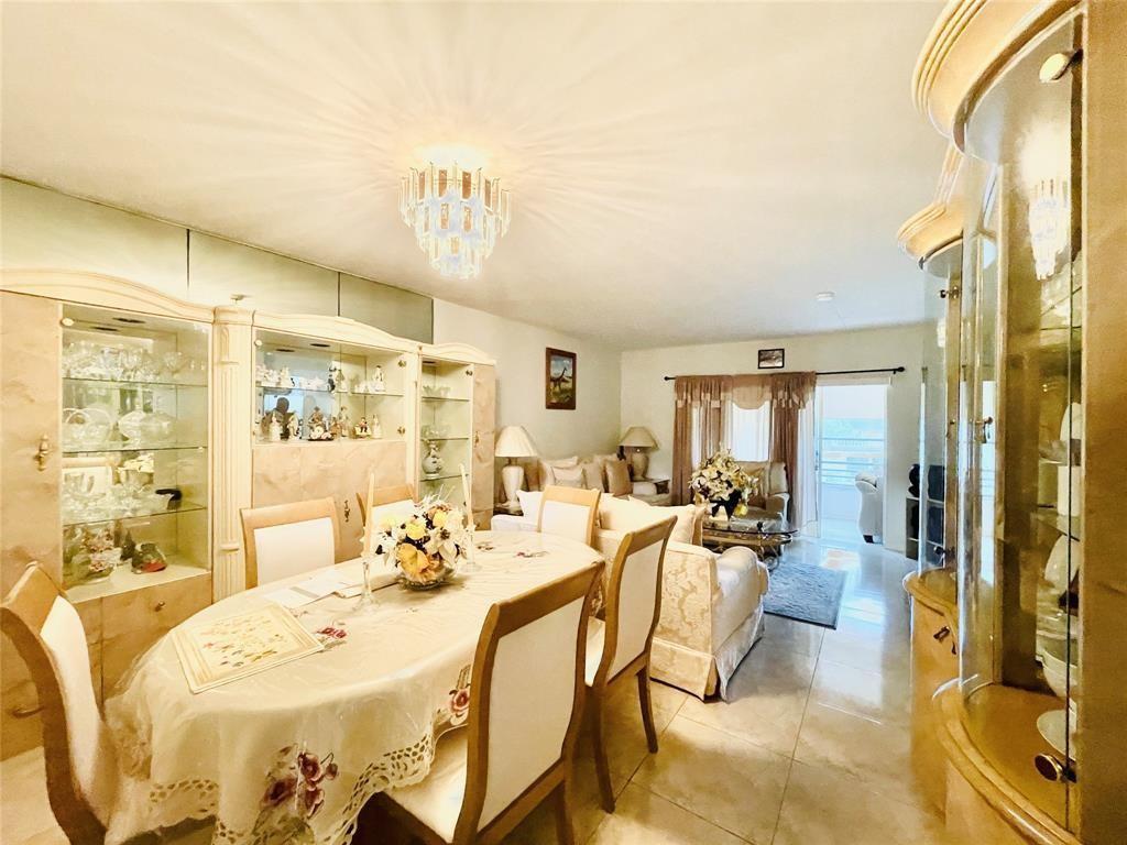 A dining area and living room feature tile floors, a crystal chandelier, and display cabinets — 7505 W Atlantic Boulevard # 208, Margate FL 33063, MARGATE, FL