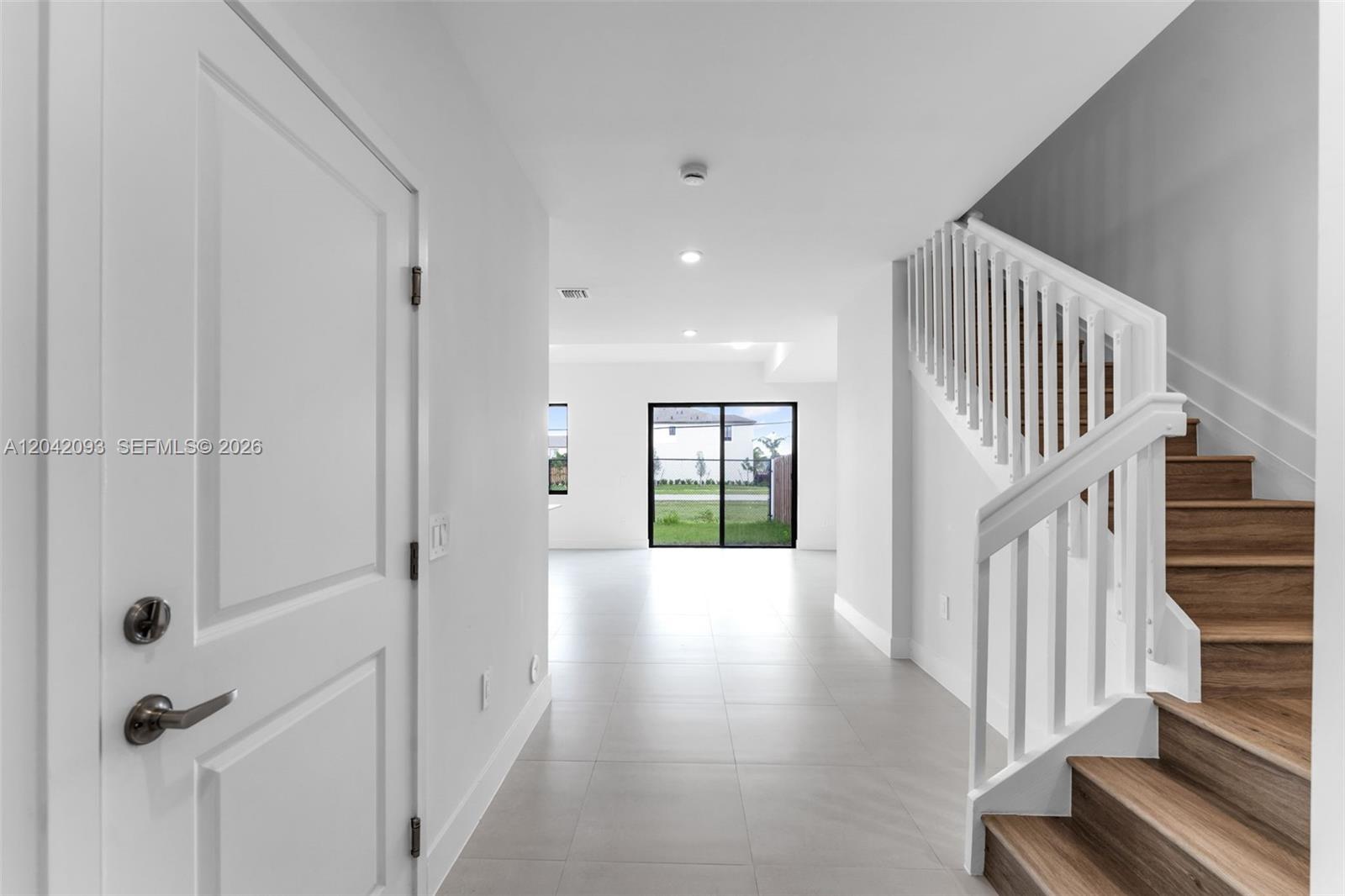 A bright entryway features light tile flooring, a white staircase, and a view of outdoors — 19107 SW 344th Ter, Homestead FL 33034, HOMESTEAD, FL