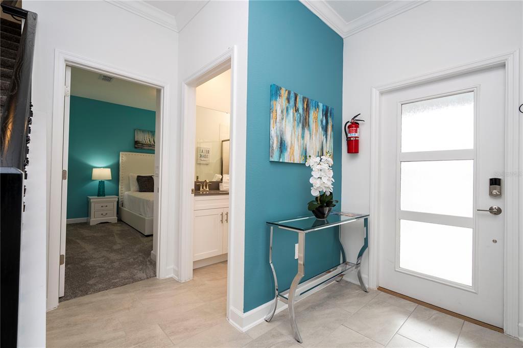 An entryway features a glass console table, a teal accent wall, and a white front door — 2569 READING TRAIL, KISSIMMEE, FL