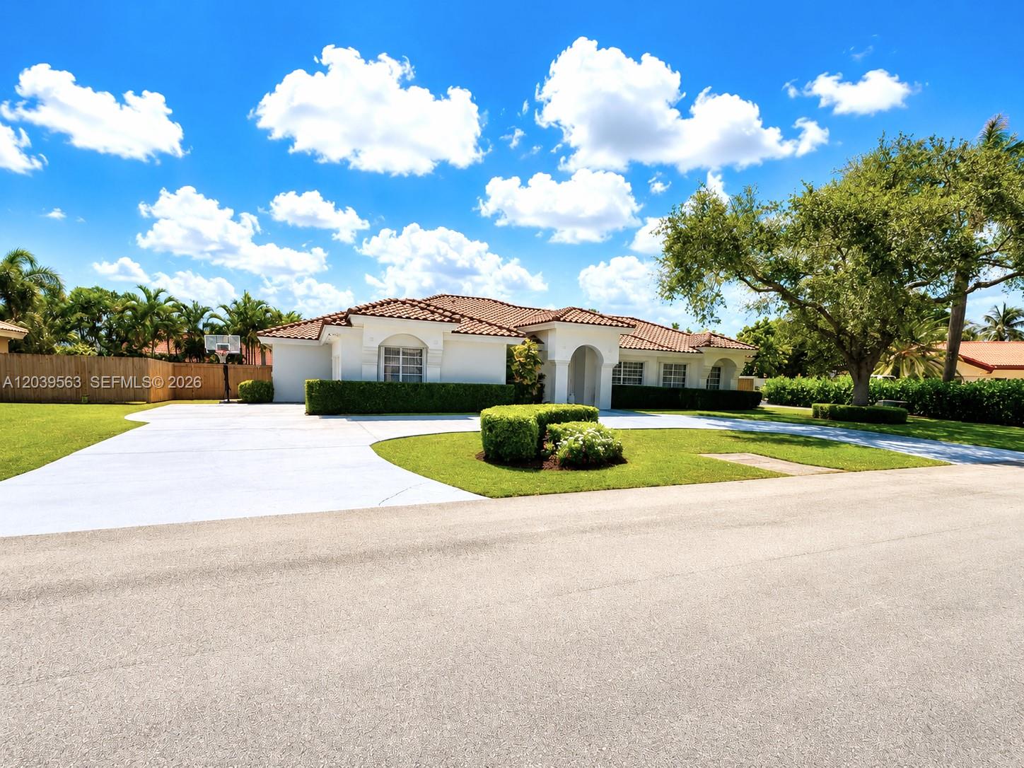 A single-story white house with a tile roof sits behind a large paved driveway — 15690 SW 153rd Ct, Miami FL 33187, MIAMI, FL