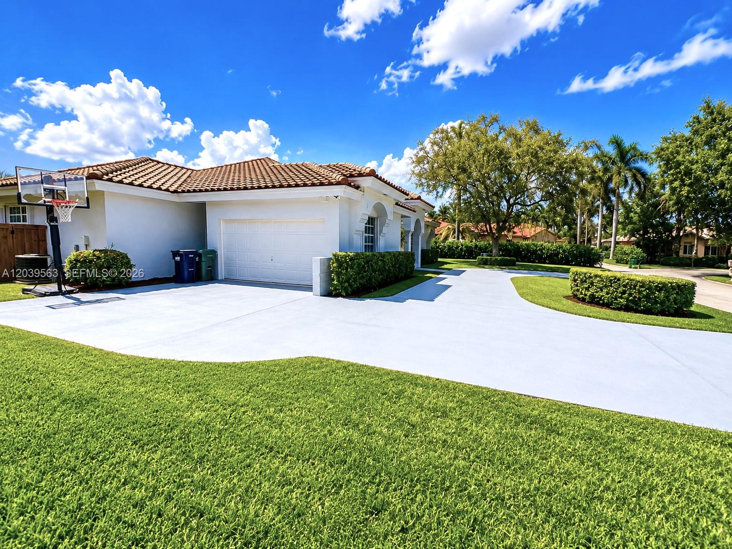 A white house with a tile roof, a paved driveway, and a basketball hoop — 15690 SW 153rd Ct, Miami FL 33187, MIAMI, FL
