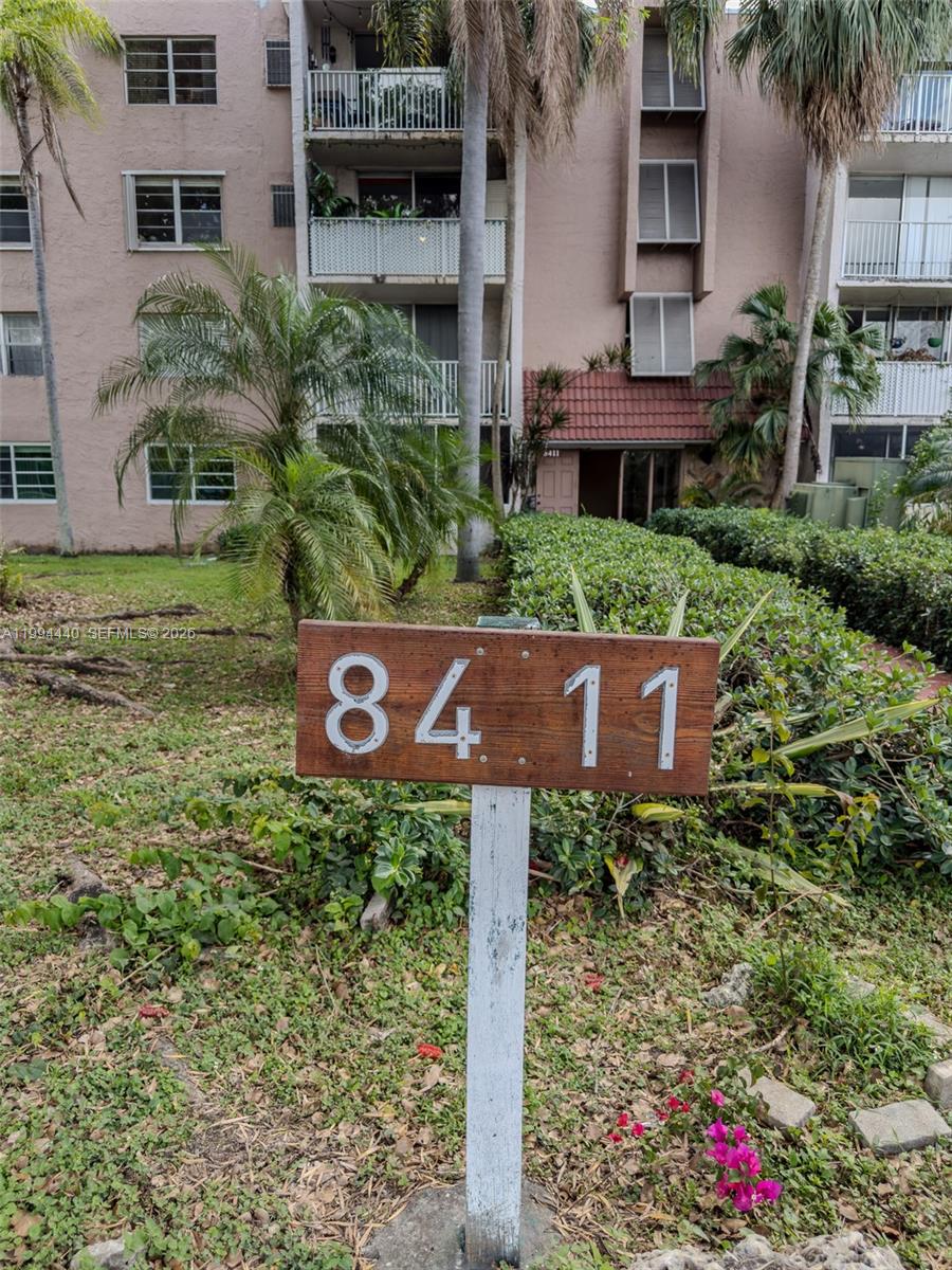A wooden sign displaying the number 8411 stands in front of a multi-story apartment building — 8411 NW 8th St # 301, Miami FL 33126, MIAMI, FL