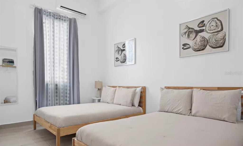 A bedroom features two beds with light-colored bedding, white walls, and two framed shell prints — 250 CALLE DEL PARQUE UNIT 3A, SAN JUAN, PR