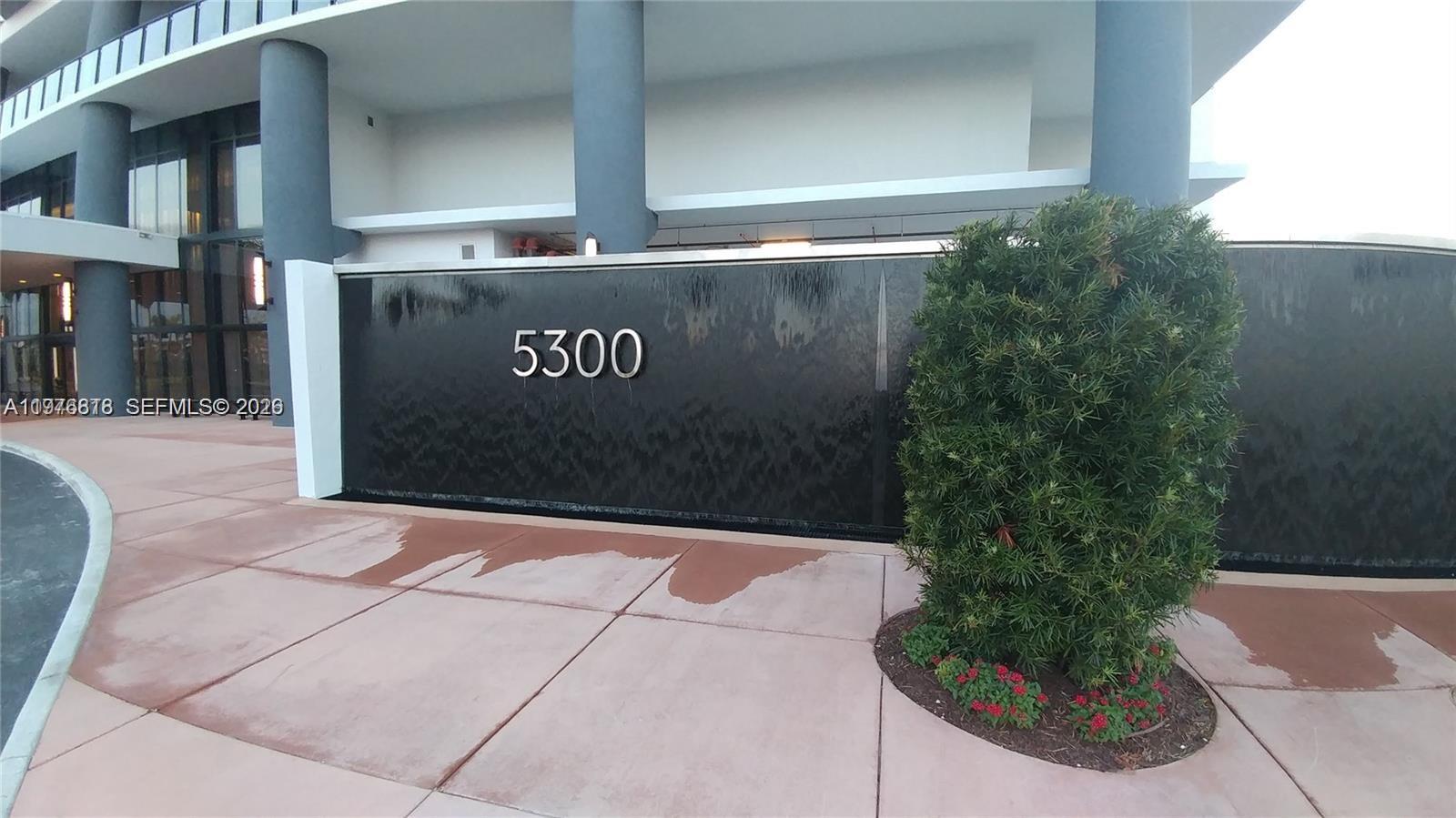 A modern building exterior features a water wall with the number 5300 and landscaping — 5300 PASEO BLVD # 1603, Doral FL 33166, DORAL, FL