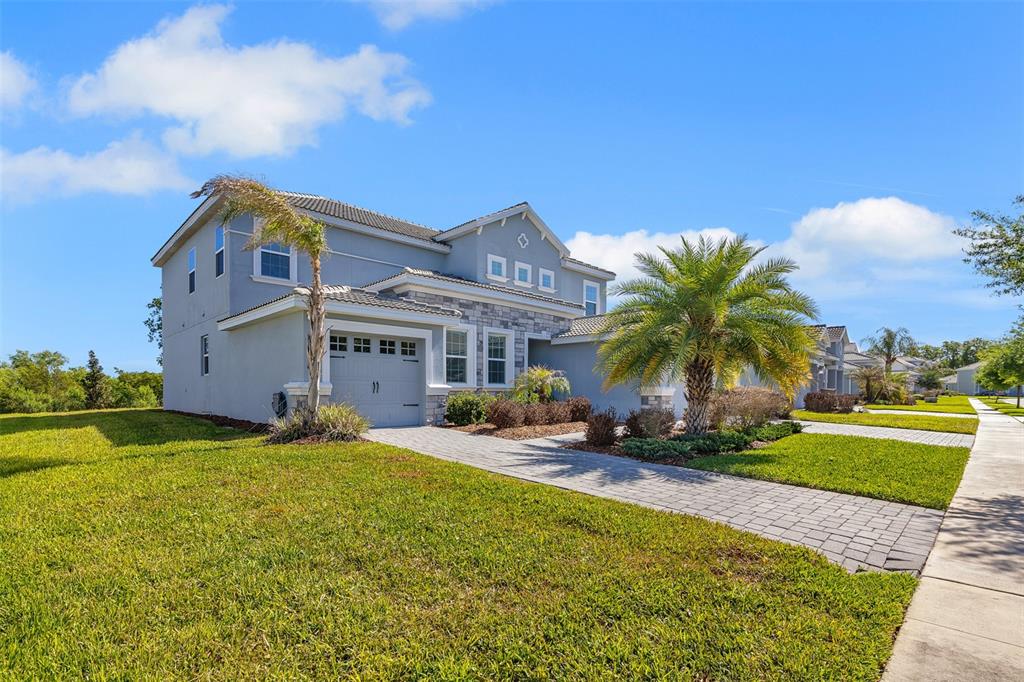 A two-story gray house with a stone facade, a paved driveway, and a palm tree — 1435 OLYMPIC CLUB BOULEVARD, CHAMPIONS GATE, FL