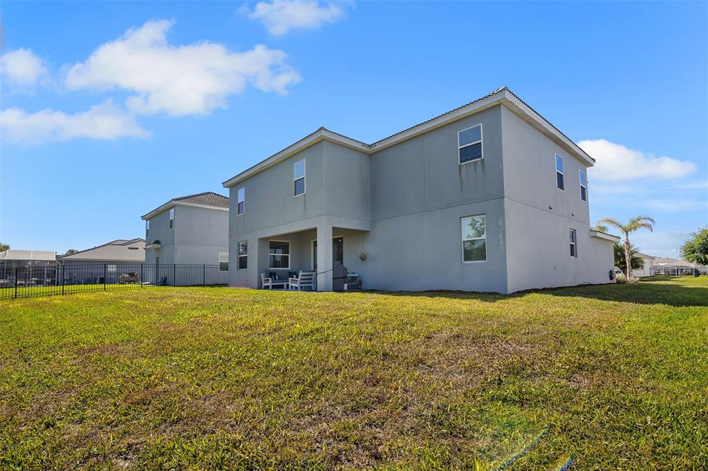 The rear exterior of a two-story house features a covered patio and a fenced yard — 1435 OLYMPIC CLUB BOULEVARD, CHAMPIONS GATE, FL