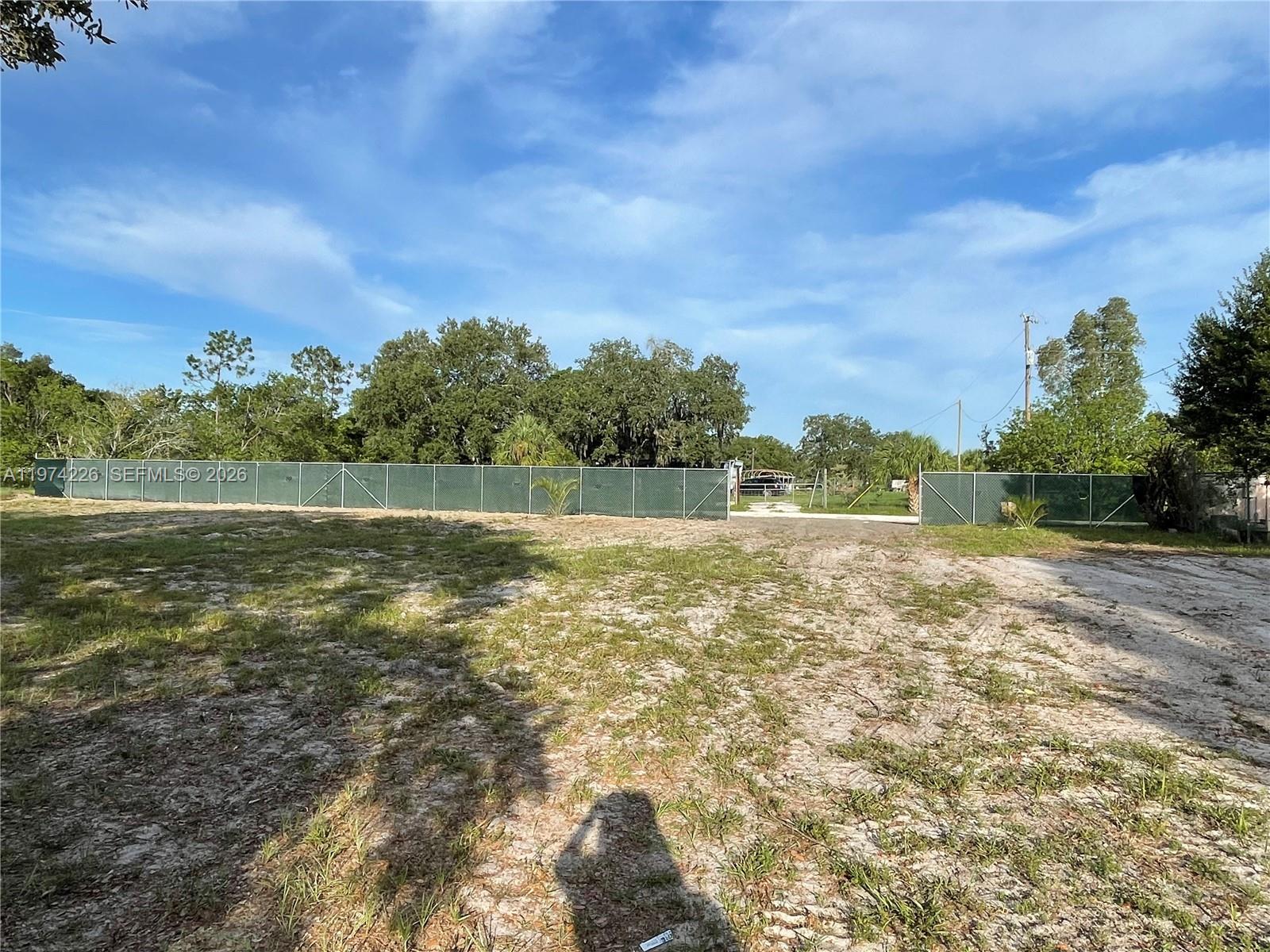 A chain-link fence with privacy screening encloses a large, sandy, undeveloped lot — 615 N Brida Street, Clewiston FL 33440, CLEWISTON, FL