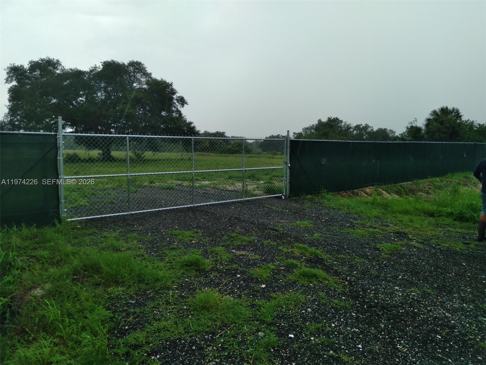 A chain-link gate and fence with privacy screening enclose a gravel lot and field — 615 N Brida Street, Clewiston FL 33440, CLEWISTON, FL