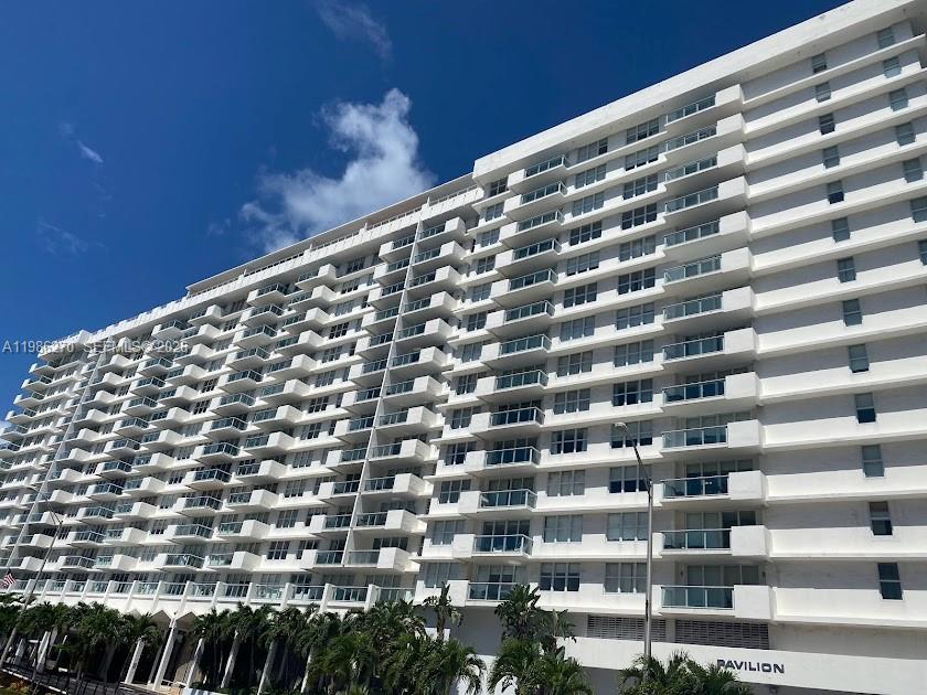 A low-angle exterior view of a large, white multi-story residential building with many balconies — 5601 Collins Ave # 1524, Miami Beach FL 33140, MIAMI BEACH, FL