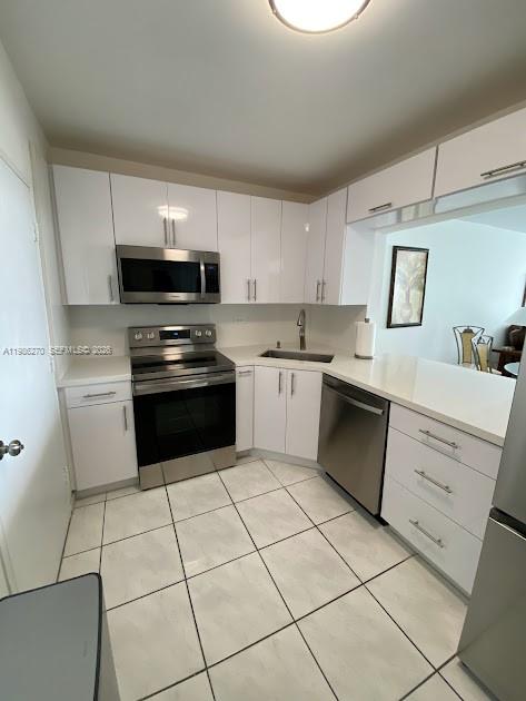 A kitchen with white cabinets, stainless steel appliances, and light-colored tile flooring — 5601 Collins Ave # 1524, Miami Beach FL 33140, MIAMI BEACH, FL