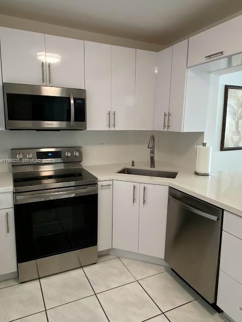 A kitchen with white cabinets, stainless steel appliances, and light-colored tile flooring — 5601 Collins Ave # 1524, Miami Beach FL 33140, MIAMI BEACH, FL