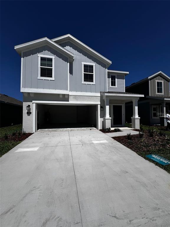A two-story house with light gray vertical siding, a two-car garage, and a concrete driveway — 433 SANDBAR LANE, HAINES CITY, FL