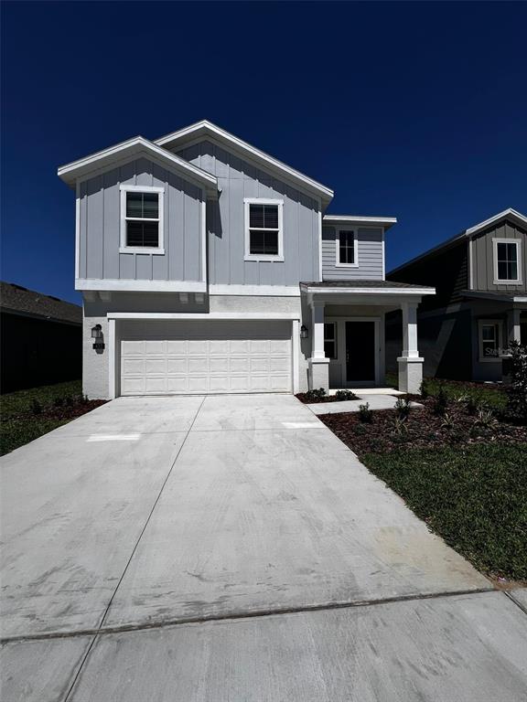 A two-story house with light gray vertical siding, a white garage door, and a concrete driveway — 433 SANDBAR LANE, HAINES CITY, FL