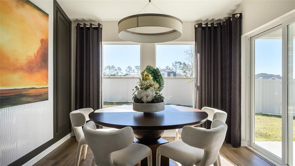 A dining room features a round wooden table, four cream chairs, and dark curtains — 9249 ORCHARD PARK LANE, DADE CITY, FL
