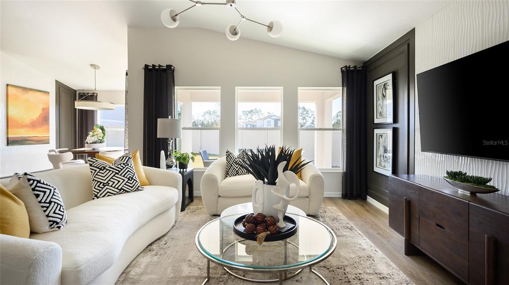 A living room features a curved white sofa, a glass coffee table, and a television — 9249 ORCHARD PARK LANE, DADE CITY, FL