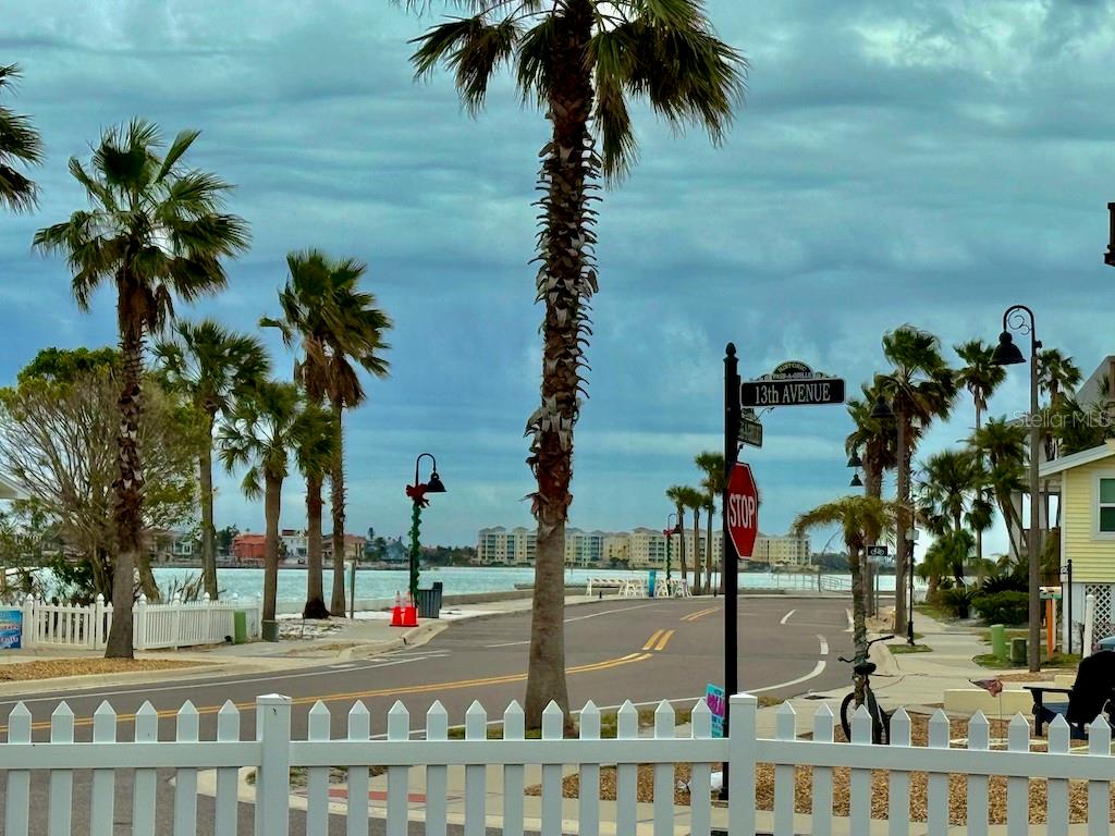 A street view featuring palm trees, a stop sign, and a white fence near water — 1300 PASS A GRILLE WAY, ST PETE BEACH, FL
