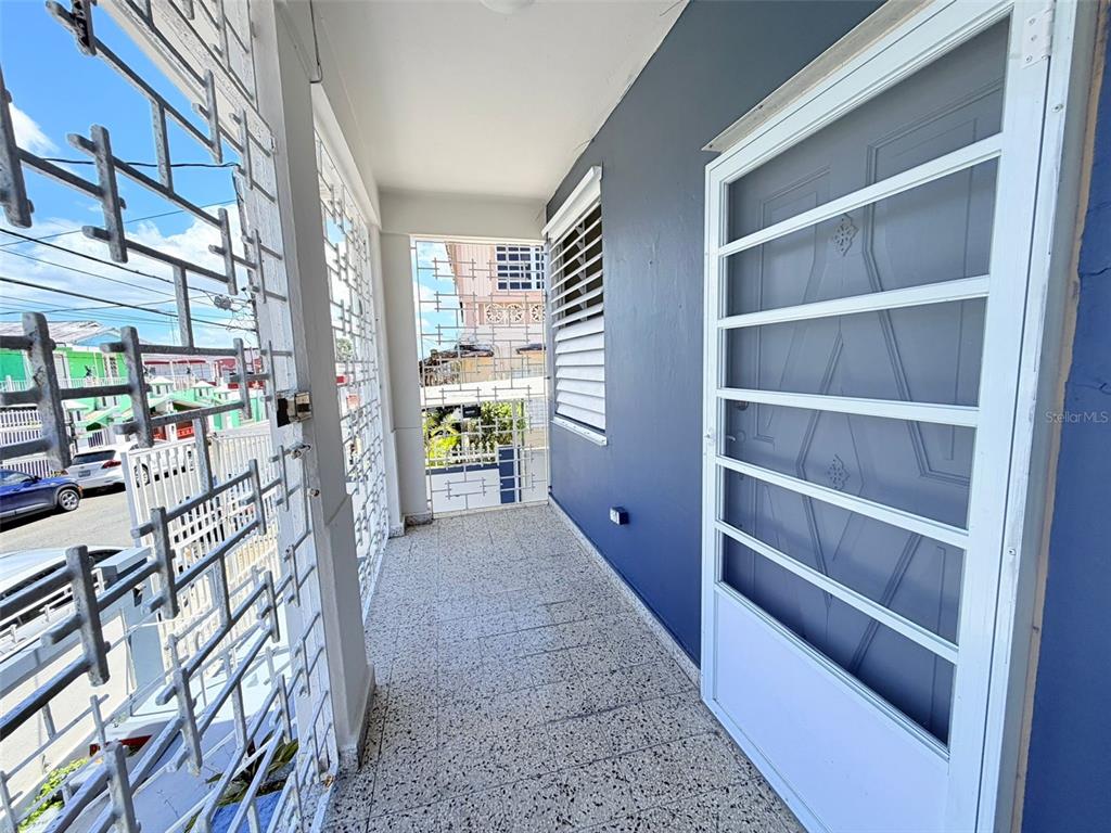 A covered balcony features a tiled floor, blue wall, and white metal security bars — 0 LIPPTT, SAN JUAN, PR