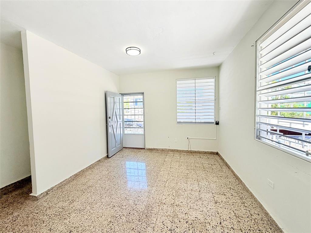 An empty room features white walls, a tiled floor, a door, and two louvered windows — 0 LIPPTT, SAN JUAN, PR