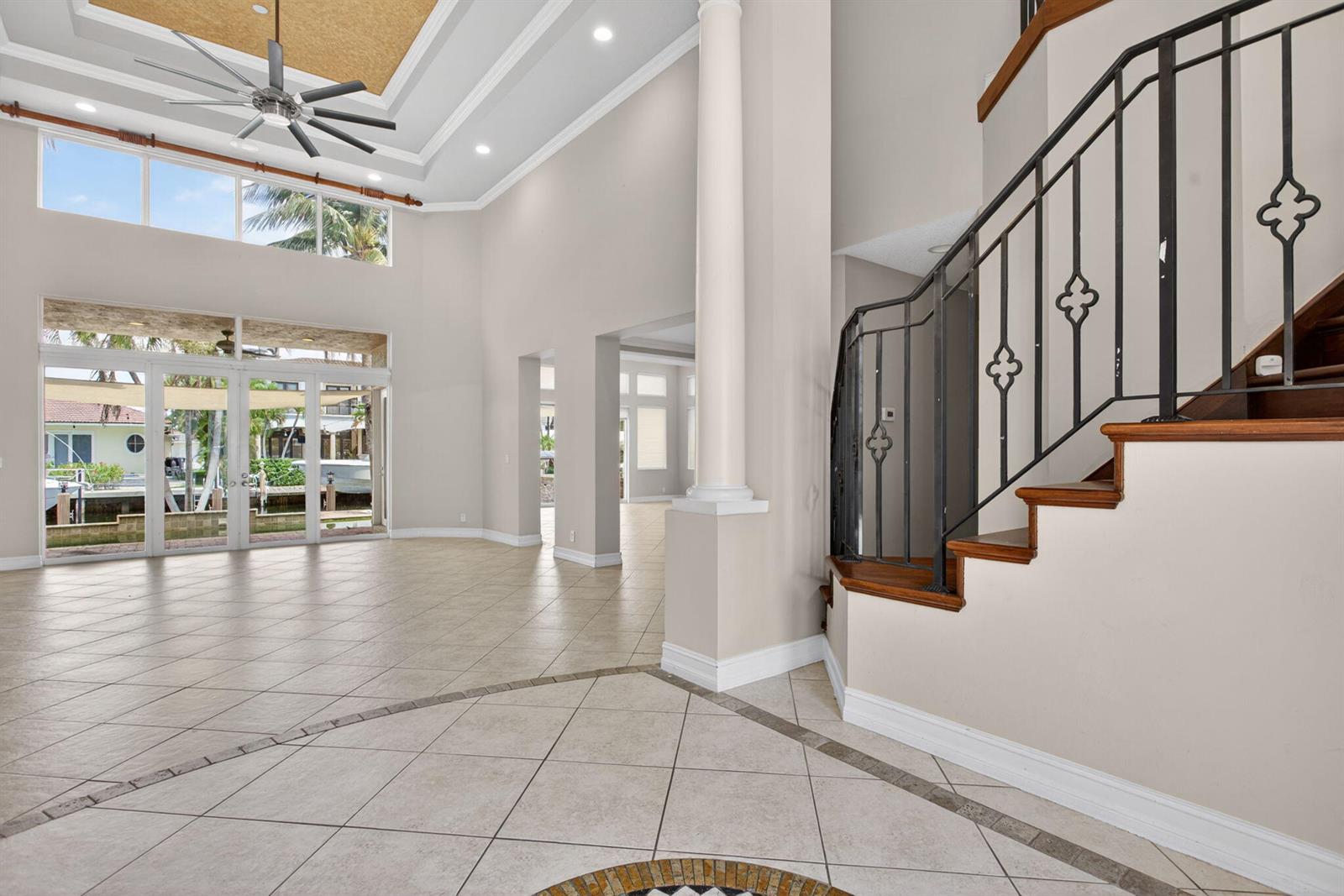 A spacious foyer with tile floors, a grand staircase, and a view of the canal — 4901 NE 29th Avenue, Lighthouse Point FL 33064, LIGHTHOUSE POINT, FL