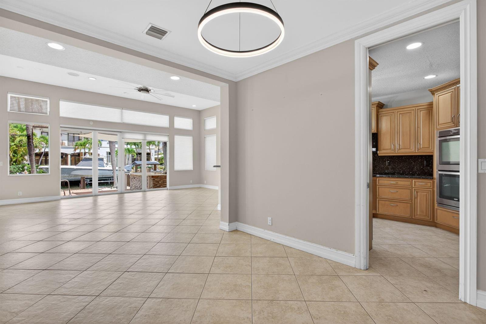 An open living area with tile floors leads to a patio overlooking a boat dock — 4901 NE 29th Avenue, Lighthouse Point FL 33064, LIGHTHOUSE POINT, FL