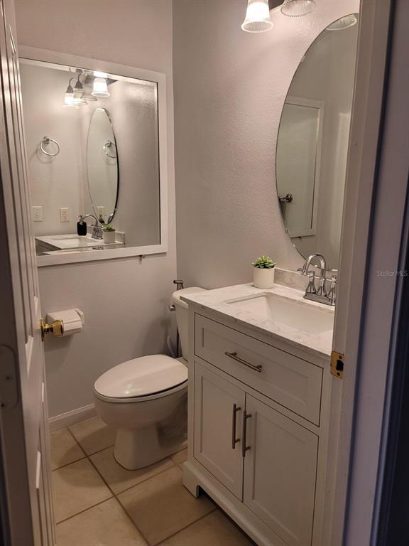A small bathroom features a white vanity with a marble countertop and a round mirror — 265 GOLDENRAIN DRIVE UNIT 265, CELEBRATION, FL