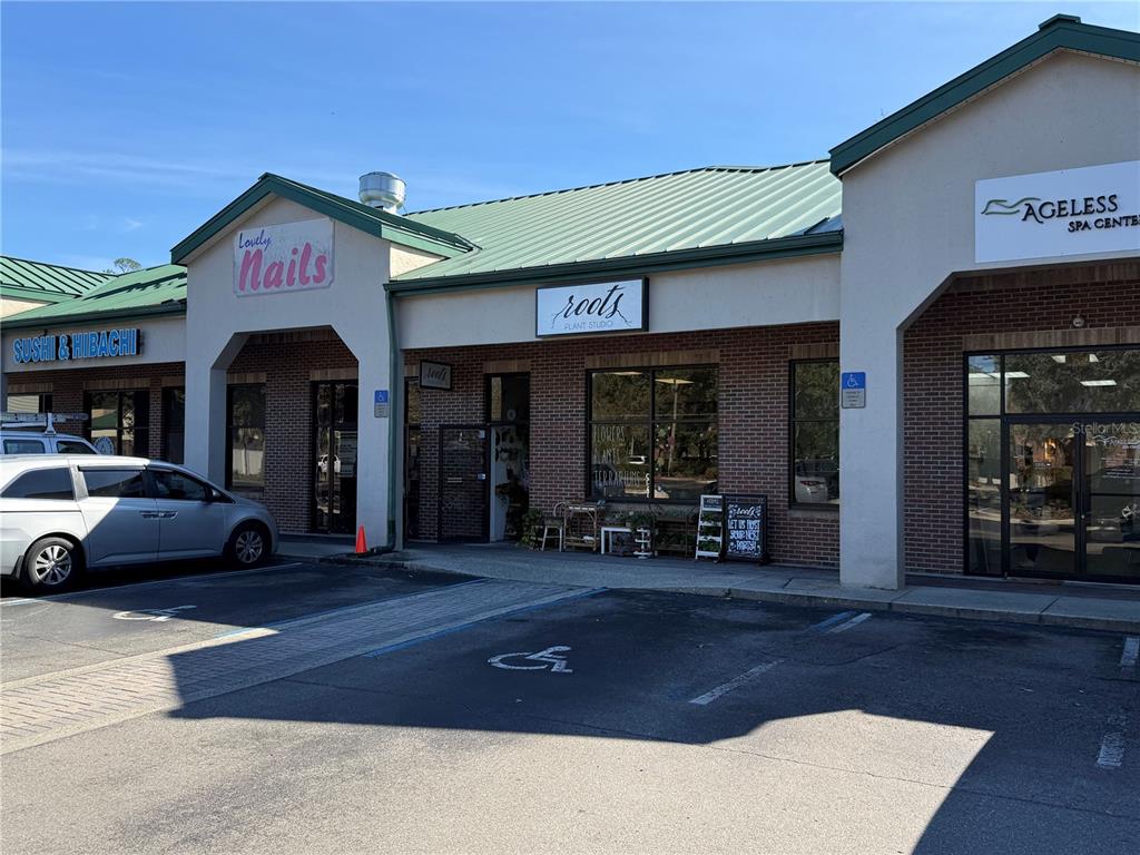 A row of commercial storefronts with brick facades and green metal roofs under a blue sky — 4780 NW 39TH AVENUE, GAINESVILLE, FL