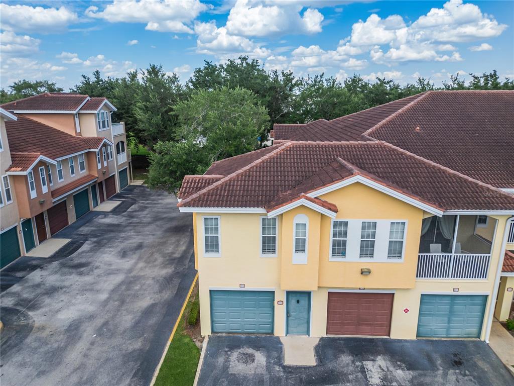 An aerial view shows the exterior of two multi-story townhomes with garages and tiled roofs — 12220 WILD IRIS WAY UNIT 101, ORLANDO, FL