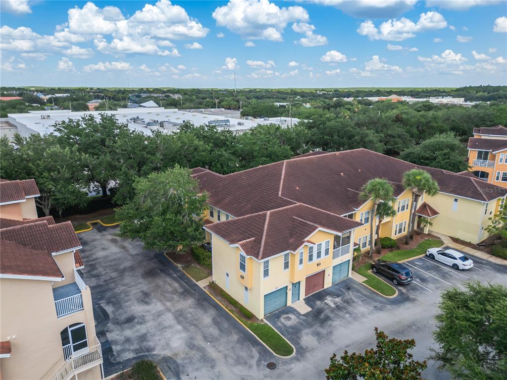 An aerial view shows a yellow multi-story apartment building with a parking lot — 12220 WILD IRIS WAY UNIT 101, ORLANDO, FL