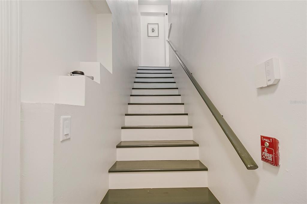 A straight staircase with dark wood treads and white risers leads to a landing — 12220 WILD IRIS WAY UNIT 101, ORLANDO, FL