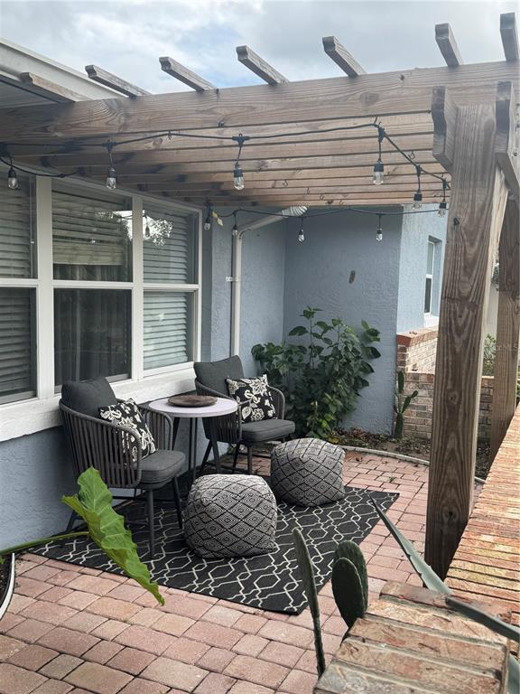A patio features a wooden pergola, string lights, outdoor chairs, and a patterned rug — 180 BEECHWOOD LANE, PALM COAST, FL
