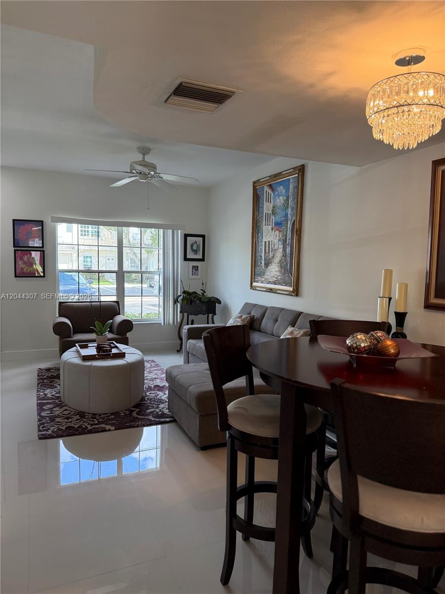 A living and dining area features a gray sofa, round ottoman, and dark wood furniture — 16619 Hemingway Dr, Weston FL 33326, WESTON, FL