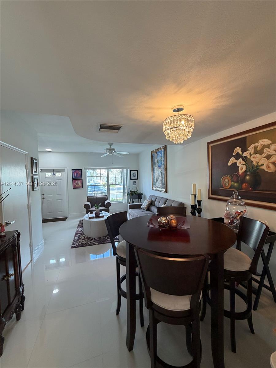 A dining area with a round table leads into a living room with tile floors — 16619 Hemingway Dr, Weston FL 33326, WESTON, FL