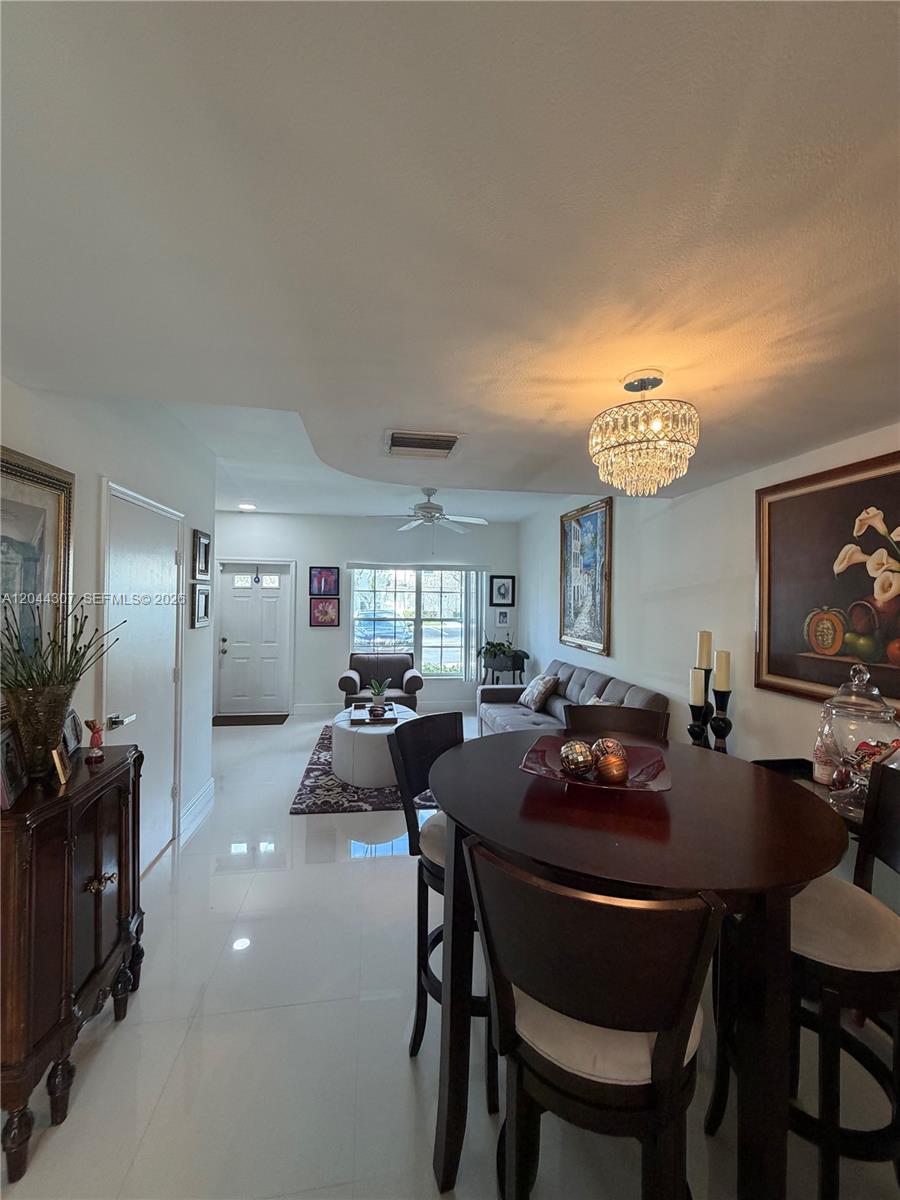 A dining area with a round table leads into a living room with a sofa — 16619 Hemingway Dr, Weston FL 33326, WESTON, FL